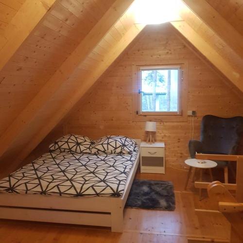 a bedroom with a bed and a chair in a attic at Domek Pod Sosnami in Kuźnica Nowa