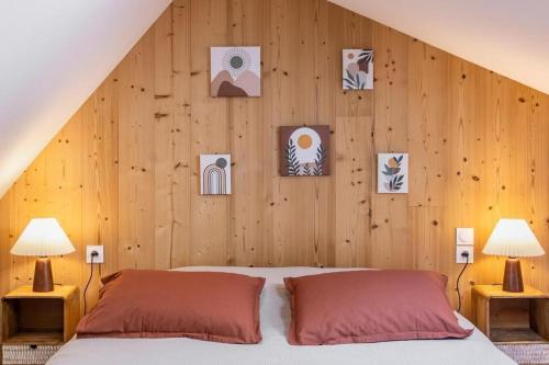 a bedroom with a wooden wall with a bed and two lamps at Ferme du Bien Hêtre Gîte Sérénité in Saint-Arnoult