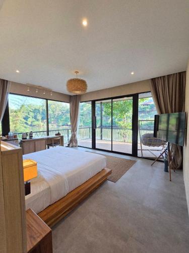 a bedroom with a large bed and a large window at Kiree River Hotel โรงแรมคิรีริเวอร์ in Ban Thong Pha Phum