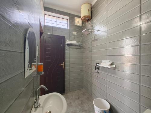 a bathroom with a sink and a brown door at Samlaun in Pauri