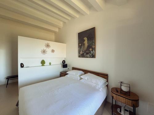 a bedroom with a white bed and a painting on the wall at ORTO NOTO - Agri Resort in Noto