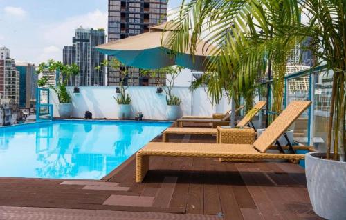 a swimming pool with two lounge chairs and an umbrella at Sapphire Hotel Silom Bangkok in Bangkok