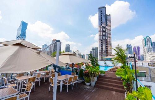 a rooftop patio with tables and chairs and a pool at Sapphire Hotel Silom Bangkok in Bangkok