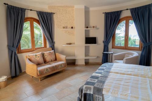 a bedroom with a bed and a chair and windows at Landhotel Can Davero in Binissalem