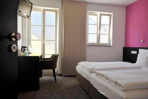 a bedroom with a bed and a desk and window at Cafe Elisabeth in Mutterstadt