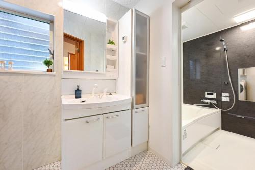 a white bathroom with a sink and a shower at The triangle hub Miyazaki in Miyazaki