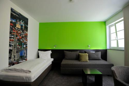 a green wall in a room with a bed and a couch at Cafe Elisabeth in Mutterstadt