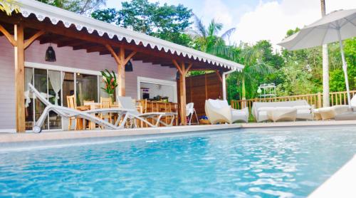 a house with a swimming pool with chairs and an umbrella at Villa Wodyétia in Quartier Ravine