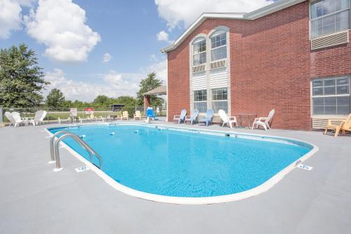 a swimming pool in front of a brick building at Super 8 by Wyndham Nixa/Springfield Area in Nixa