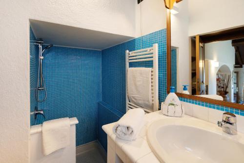 a bathroom with a white sink and a blue tile wall at Paradiso San Giacomo in Cogorno