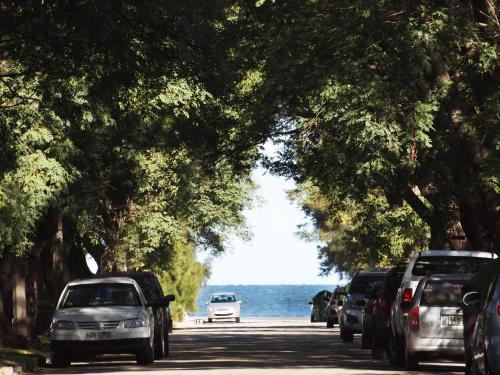 a row of cars parked on a road next to the water at Cottage Carrasco in Montevideo