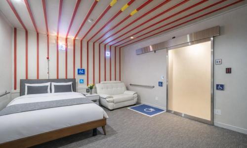a bedroom with a bed and a chair in a room at Sasang Goyohan-hotel in Busan