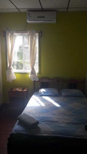 a bedroom with a bed and a window with curtains at Bastimentos Caribean Hotel in Bocas Town