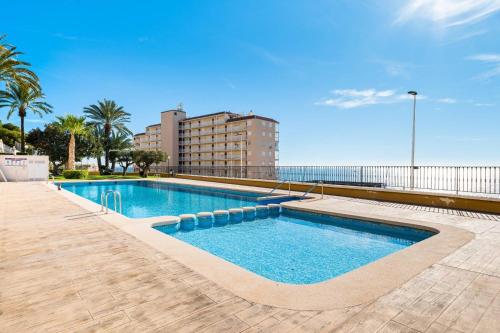 a swimming pool next to a building and the ocean at Tabarca’s View Santa Pola in Santa Pola