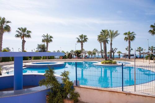 a pool at a resort with palm trees at Aguamarina Ático Duplex Gran Terraza Cabo Roig in Orihuela