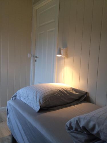 a bedroom with a bed with a light on the wall at Bustad in Larseng
