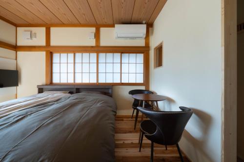 a bedroom with a bed and a table and chairs at 金木犀 in Kesennuma
