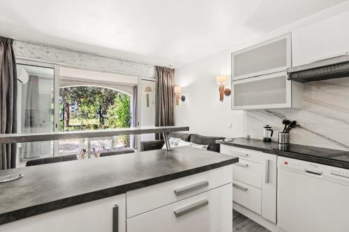 a kitchen with white cabinets and a large window at Apartment – Restanques – Swimming in Grimaud