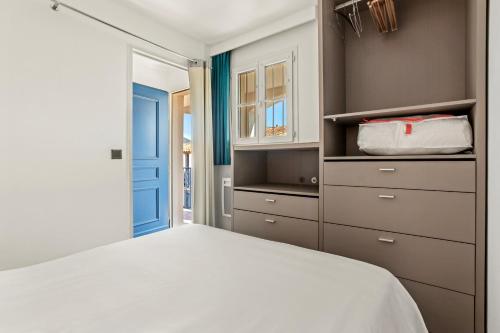 a bedroom with a white bed and a blue door at Apartment – Restanques – Swimming in Grimaud