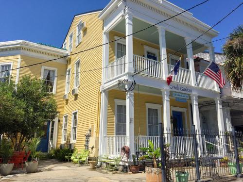 a yellow house with a woman sitting in front of it at Creole Gardens Guesthouse and Inn in New Orleans