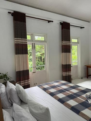 a bedroom with a bed and two windows at Kandy Home stay - Haloluwa in Katugastota