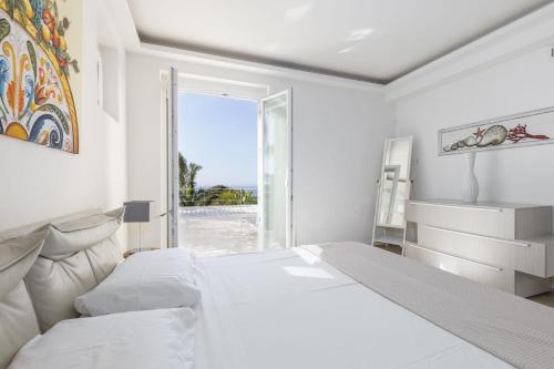 a white bedroom with a large bed and a window at Villa Annalisa by PosarelliVillas in Pizzolungo