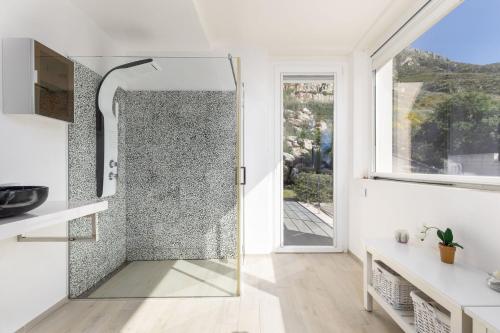 a glass shower in a white bathroom with a window at Villa Annalisa by PosarelliVillas in Pizzolungo
