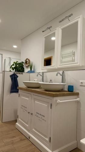 a white bathroom with two sinks and a refrigerator at Floating-Haus Meerferien in Bitterfeld