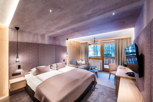 a hotel room with a large bed and a television at Hotel Sonnalp 4 Sterne Superior in Obereggen