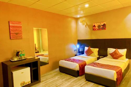a hotel room with two beds and a mirror at FabHotel Ace Prime in Greater Noida