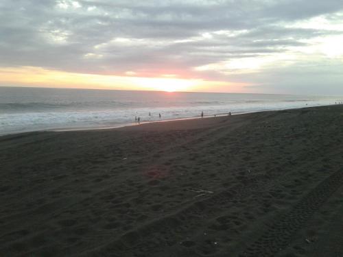 a group of people on the beach at sunset at Villa Tortugas in Monterrico