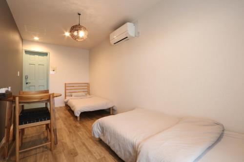 ein Schlafzimmer mit zwei Betten, einem Tisch und einem Spiegel in der Unterkunft Re AERU in Minamiboso