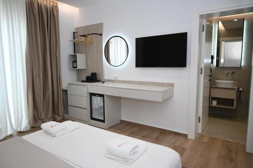 a white room with a bed and a sink and a mirror at Belmond Hotel in Ksamil