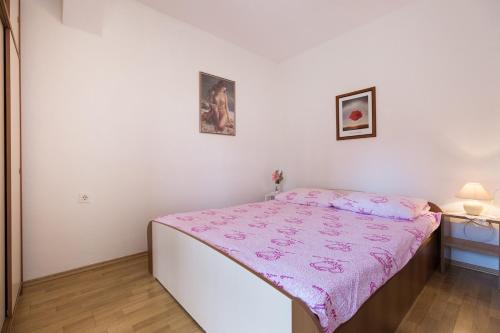 a small bedroom with a bed with a pink blanket at House on the sea in Preko