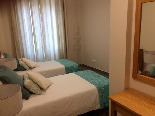 a hotel room with two beds and a mirror at Apartamentos Sousa in Funchal