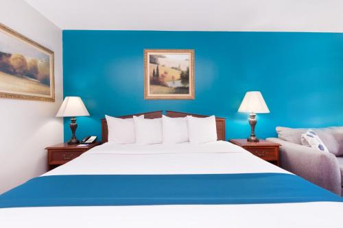 a bedroom with a large bed with a blue wall at Baymont by Wyndham Duncan/Spartanburg in Duncan