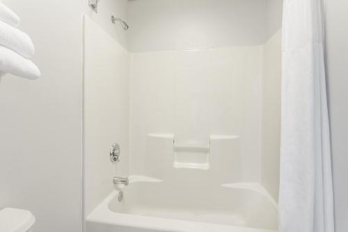a white bathroom with a tub and a shower with a shower curtain at Baymont by Wyndham Duncan/Spartanburg in Duncan