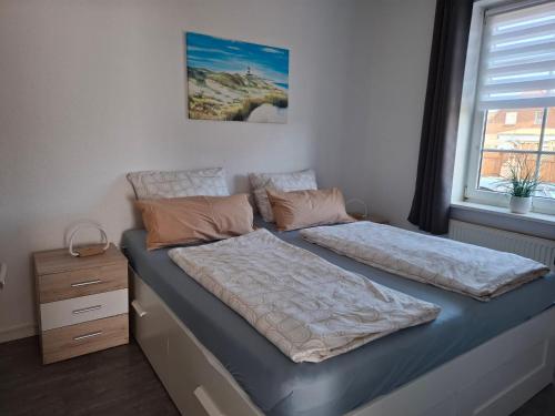 a bedroom with two twin beds and a window at Ferienwohnungen Schmitz in Wangerland