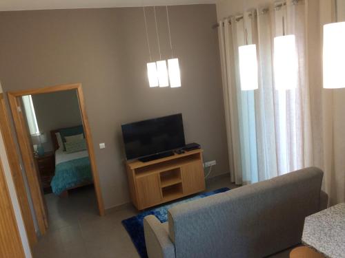 a living room with a tv and a couch and a mirror at Apartamentos Sousa in Funchal
