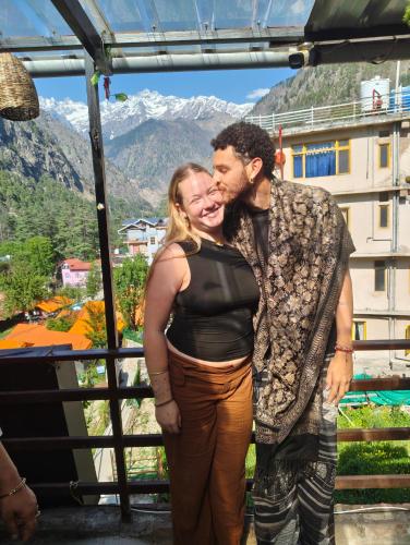 a man and woman posing for a picture in front of a mountain at Kasolview Homestay and Peace Inn Cafe in Kasol