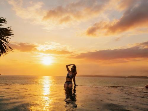a woman standing in the water at the beach at sunset at Boton Blue Hotel & Spa in Nha Trang