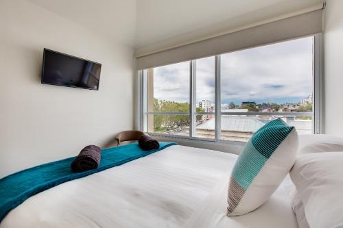 a bedroom with a large bed with a large window at Salamanca Galleria Apartments in Hobart
