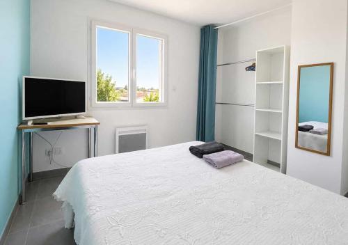 a white bedroom with a bed and a television at Chambres d'hôtes Drome in Chatuzange-le-Goubet
