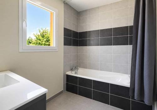 a bathroom with a tub and a sink and a window at Chambres d'hôtes Drome in Chatuzange-le-Goubet