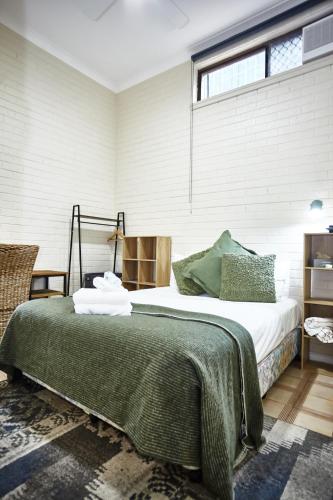 a bedroom with a bed with a green blanket on it at Lismore Hillside Home on Ballina Road in Lismore