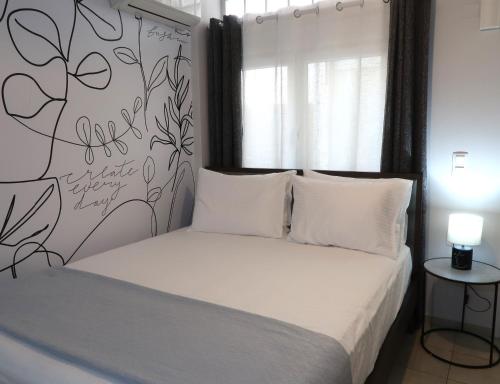 a bedroom with a white bed and a wall with flowers at BeCozy in Thérissos