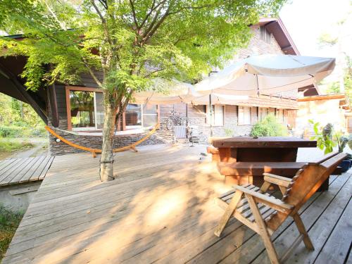 a wooden deck with a table and an umbrella at Kunugi Relaxation with 4 modern rooms in Hakuba