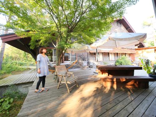 a woman is standing on a wooden deck at Kunugi Relaxation with 4 modern rooms in Hakuba