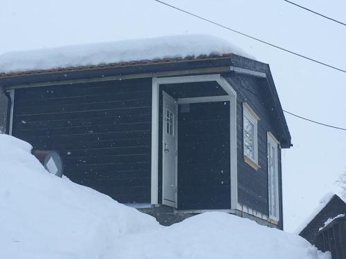 a black building with a door in the snow at Voss- Myrkdalen Lodge in Vossestrand