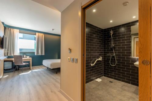 a room with a bathroom with a shower and a bedroom at Travelodge Bilbao Sestao in Sestao
